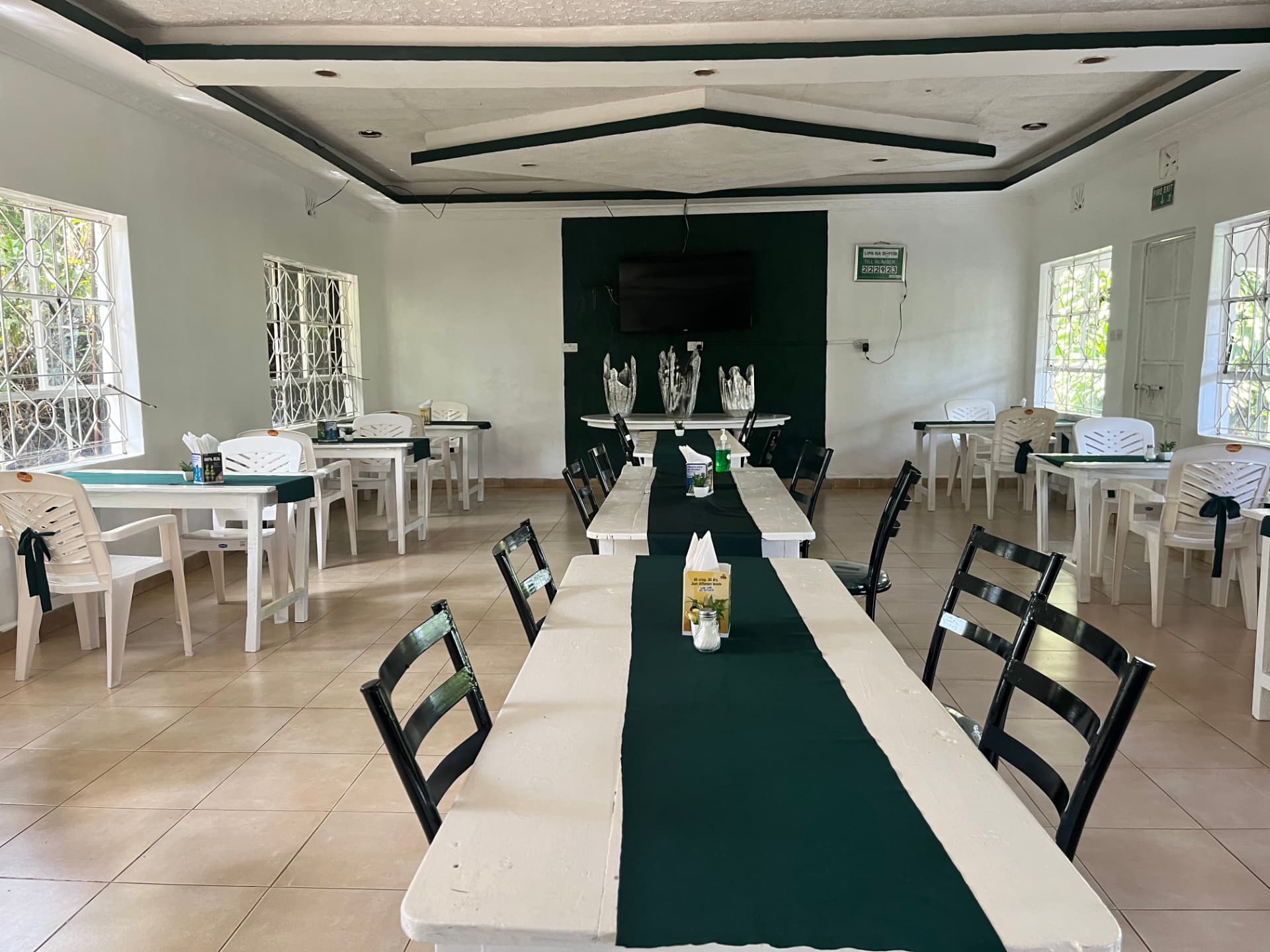 Indoor dining hall with white tables and green runners